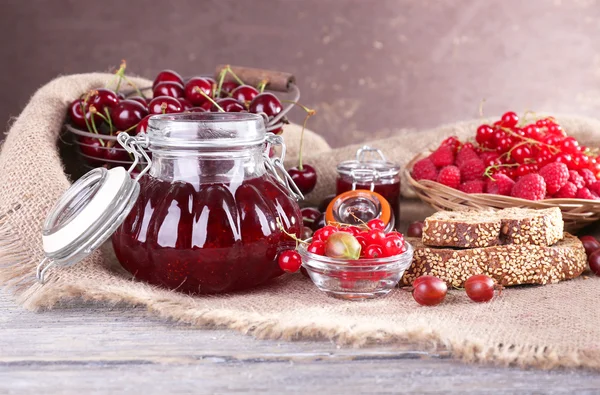 Jam in glazen pot op tafel, bessen close-up — Stockfoto