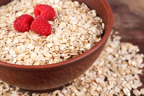 Große braune Schüssel mit Haferflocken und Beeren auf einem Holztisch — Stockfoto