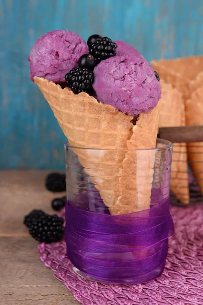 Gelato gustoso con bacche in cono di cialda su fondo di legno blu — Foto Stock