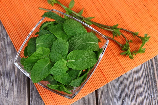 Glazen vierkante kom van mint verlaat op een oranje servet op houten achtergrond — Stockfoto