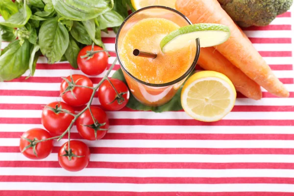 Glass of fresh carrot juice and vegetables on table cloth — Stock Photo, Image