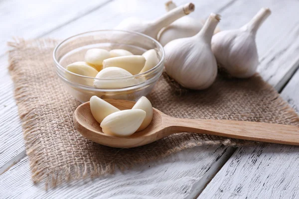 Fresh sliced garlic in glass bowl on wooden background — Stock Photo, Image
