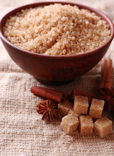 Cubes de sucre brun et sucre cristallin, épices dans un bol sur fond de sac — Photo