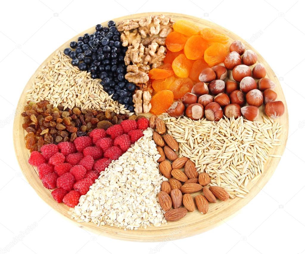 Big round plate with raisins, raspberries, oatmeal, nuts and dried apricots divided on sectors on white background isolated