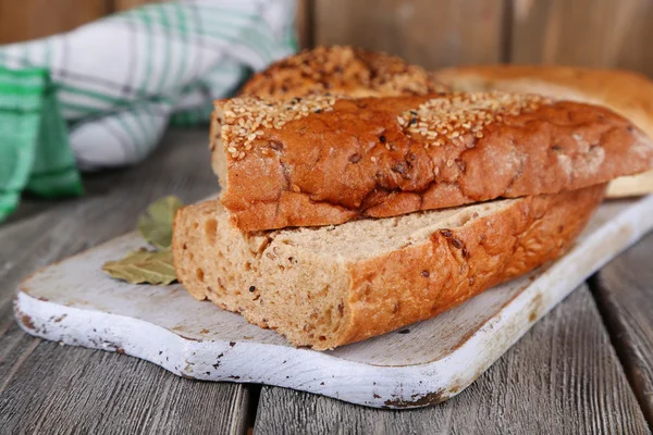 Ahşap zemin üzerinde kesme tahtası üzerinde taze pişmiş ekmek — Stok fotoğraf