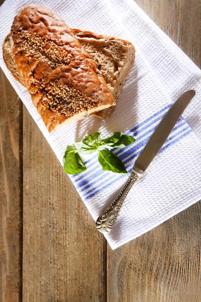 Pan recién horneado y albahaca fresca en toalla de cocina, sobre fondo de madera — Foto de Stock