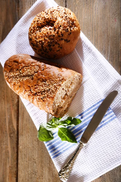 Frisch gebackenes Brot und frisches Basilikum auf Küchentuch, auf Holzgrund — Stockfoto