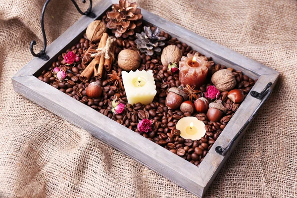 Candles on vintage tray with coffee grains and spices, bumps on sackcloth background — Stock Photo, Image