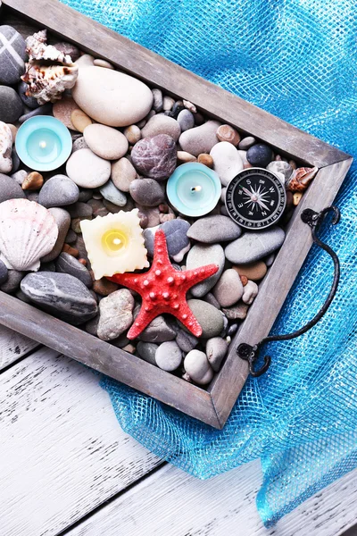 Vintage tepsi Denizi çakıl taşları ile deniz yıldızı ve deniz kabukları ahşap zemin üzerine mum — Stok fotoğraf