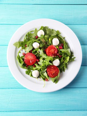 roka, domates, peynir mozzarella toplar ve plaka renk ahşap zemin üzerine susam ile yapılan yeşil salata