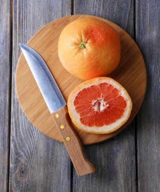 Olgun greyfurt ve ahşap zemin üzerinde kesme tahtası üzerinde bıçak