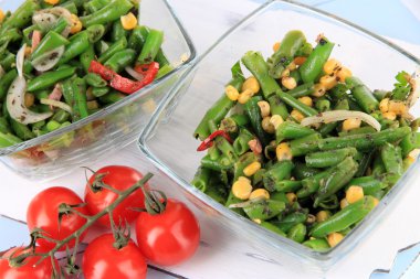 ahşap zemin üzerine yeşil fasulye, jambon ve bardakta mısır salatası kaseler