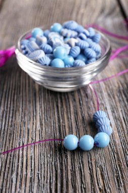 küçük cam kapta ve ahşap zemin üzerine dantel boncuk