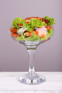 gri zemin üzerine ahşap masa üzerinde bir kadeh marulla taze haşlanmış karides