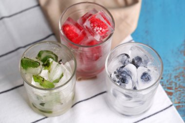 buz küpleri ile nane yaprakları, ahududu ve gözlük, blueberry renk ahşap arka plan üzerinde