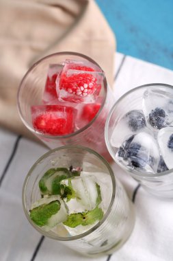 buz küpleri ile nane yaprakları, ahududu ve gözlük, blueberry renk ahşap arka plan üzerinde