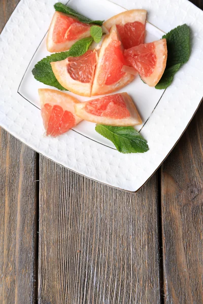 Mogna hackade grapefrukt med mynta blad på plattan, på trä bakgrund — Stockfoto