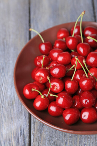 Sweet cherries  on plate on wooden background