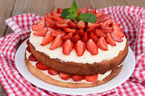 Delicious biscuit cake with strawberries on table close-up — Stock Photo, Image