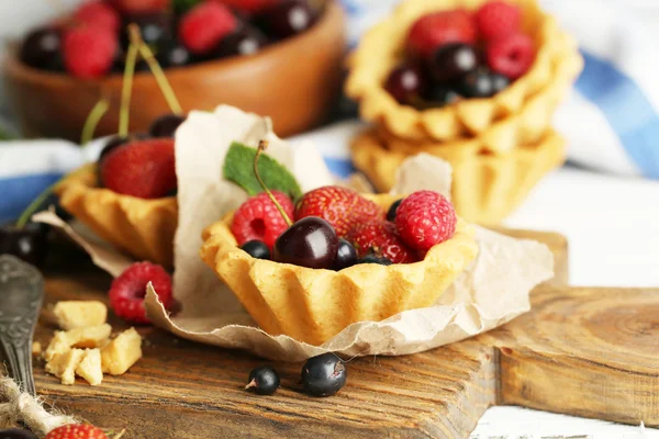 Tasty tartlets with berries on wooden table — Stock Photo, Image