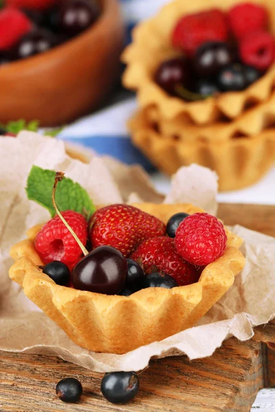 Tasty tartlets with berries on wooden table — Stock Photo, Image