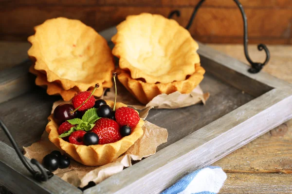 Смачні тарталетки з ягодами на дерев'яному підносі — стокове фото