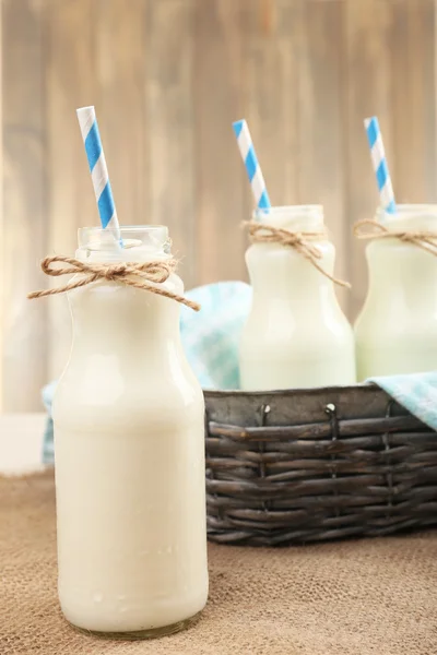 Leche en botellas con paja de papel sobre la mesa — Foto de Stock