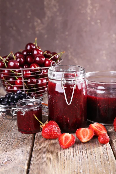 Jam in glazen pot op tafel, bessen close-up — Stockfoto