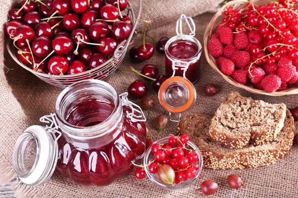 Jam in glazen pot op tafel, bessen close-up — Stockfoto