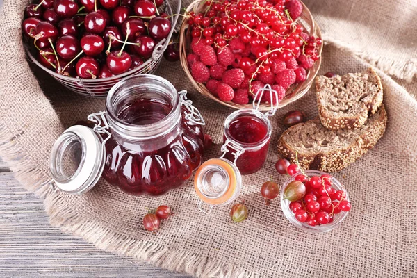 Jam in glazen pot op tafel, bessen close-up — Stockfoto