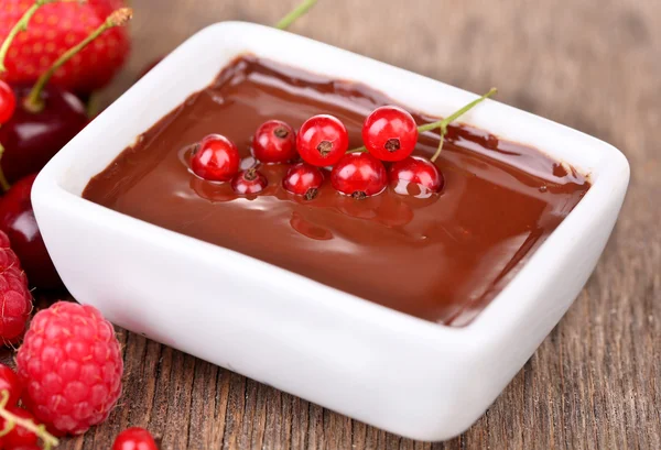 Ripe sweet berries and liquid chocolate on wooden table — Stock Photo, Image