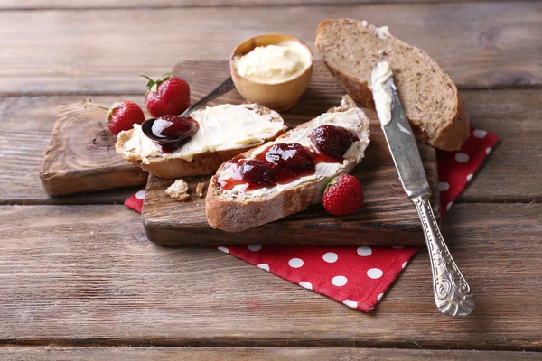 Verse toast met zelfgemaakte boter en strawberry jam op houten achtergrond — Stockfoto