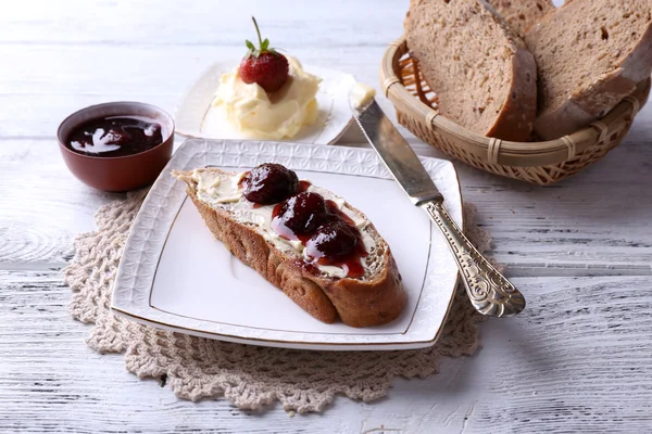 Свежие тосты с домашним маслом и клубничным джемом на светлом деревянном фоне — стоковое фото