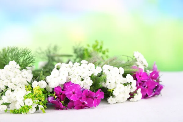 Corona de flores sobre mantel de tela blanca sobre fondo natural — Foto de Stock