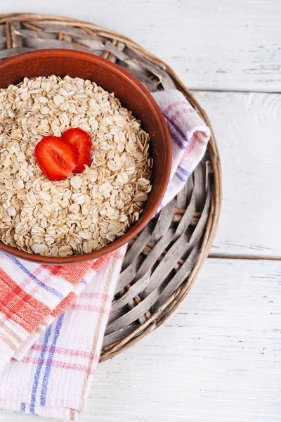 Big brown bowl with oatmeal and berries on a napkin on white wooden table — Stock Photo, Image