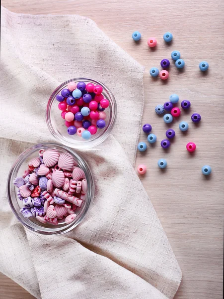 Olika pärlor i glas skålar på tyg på bord — Stockfoto