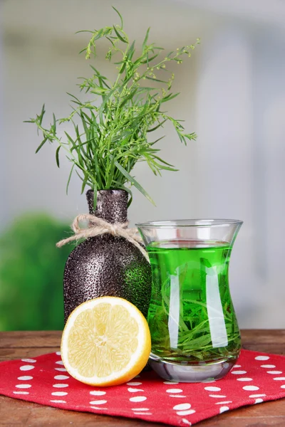 Estragon-Getränk mit Zitrone auf Holztisch vor hellem Hintergrund — Stockfoto