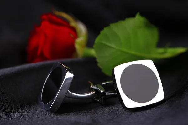 Pair of cuff links with red rose on black silk fabric background — Stock Photo, Image