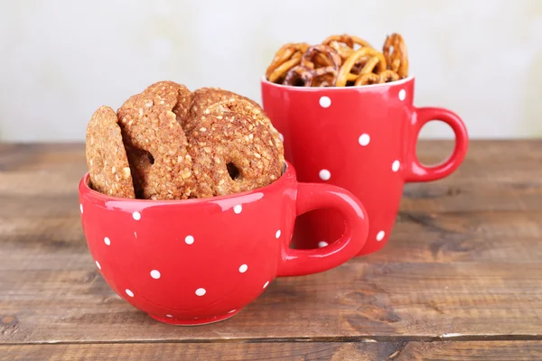 Trockenes Frühstück, Sticks und Kekse in roter Tasse und Teller auf einem Holztisch — Stockfoto