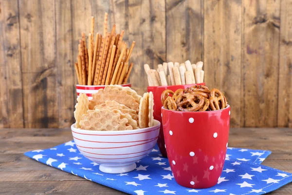 Petit déjeuner sec, bâtonnets et biscuits dans une tasse à pois rouges et assiette sur une serviette sur fond en bois — Photo