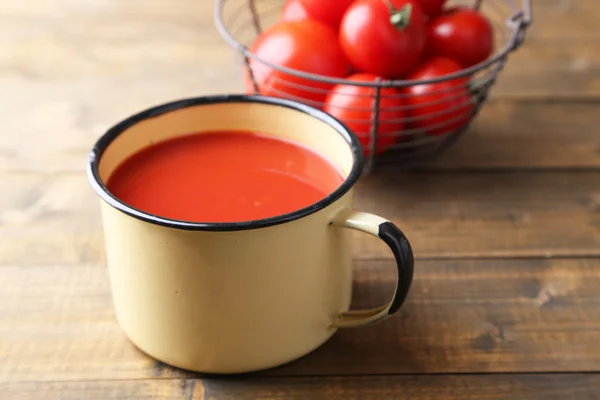 Sumo de tomate caseiro na caneca a cores e tomates frescos no fundo de madeira — Fotografia de Stock