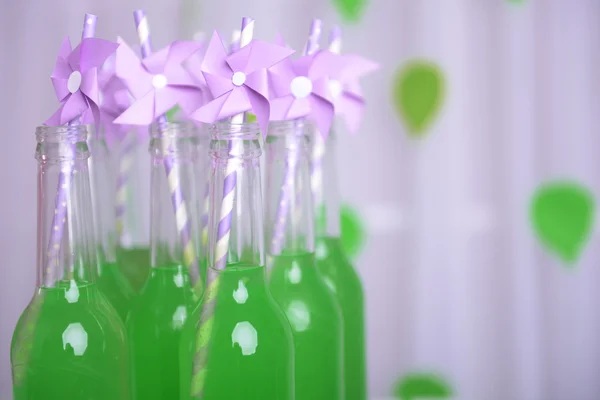 Bottles of drink with straw on decorative background — Stock Photo, Image