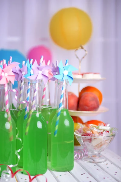 Botellas de bebida con paja y frutas sobre fondo decorativo —  Fotos de Stock