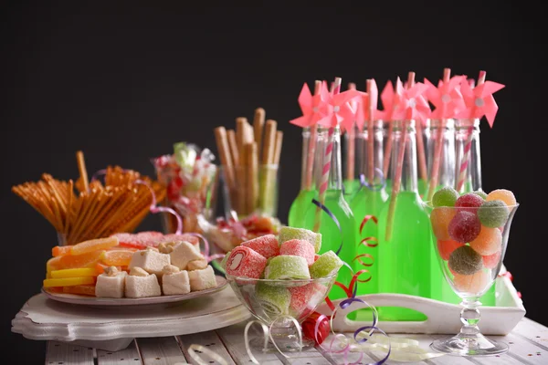 Botellas de bebida con paja y dulces sobre fondo oscuro —  Fotos de Stock