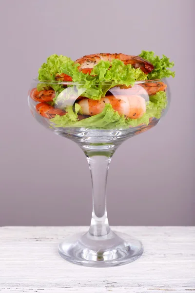 Čerstvé vařené krevety s hlávkovým salátem v poháru na dřevěný stůl na šedém pozadí — Stock fotografie