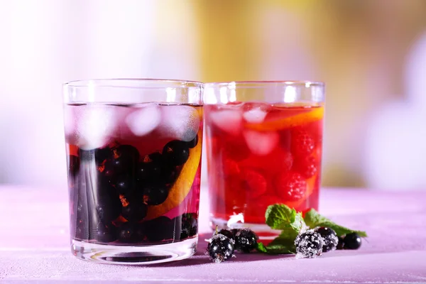 Glasses of cold berry cocktail with lemon on wooden table — Stock Photo, Image