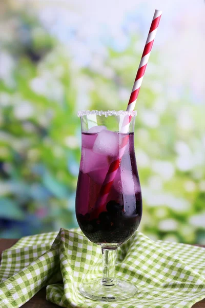 Glass of cold berry cocktail and napkin on wooden table — Stock Photo, Image