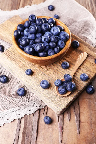 Wooden bowl of blueberries on cutting board on sacking napkin on wooden background — Stock Photo, Image