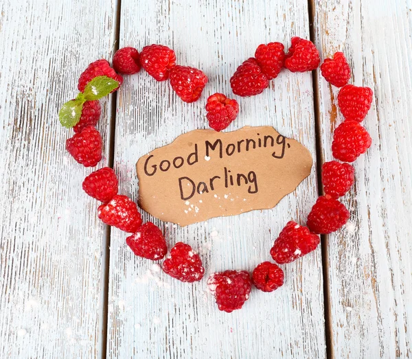 Heart shaped raspberries on wooden background — Stock Photo, Image