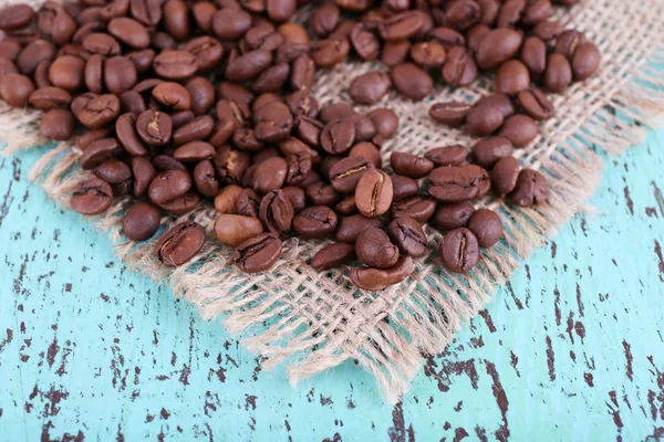 Kaffeebohnen auf Sackserviette auf blauem Holzhintergrund — Stockfoto